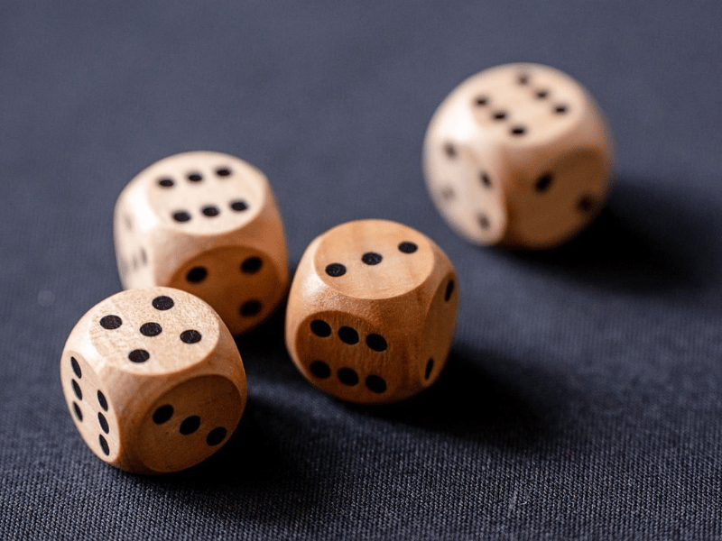 Set of four wooden dice with black dots and rounded edges